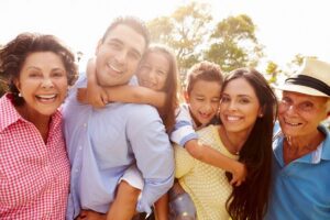 picture of a family with dad having daughter on his back, and mom having son on her back and the grandparents on either side.