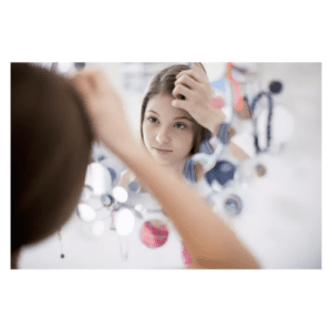stock picture of a girl looking into the mirror at herself checking her image.